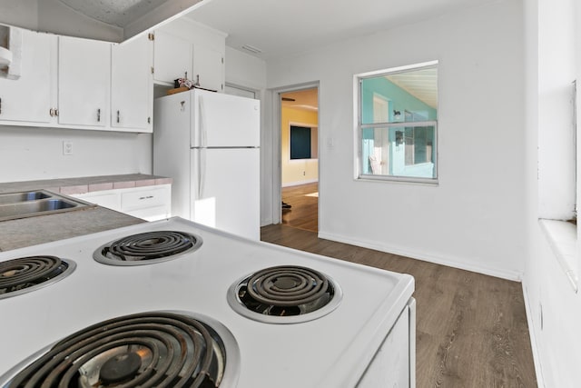 kitchen with white cabinets, white refrigerator, sink, dark hardwood / wood-style floors, and range