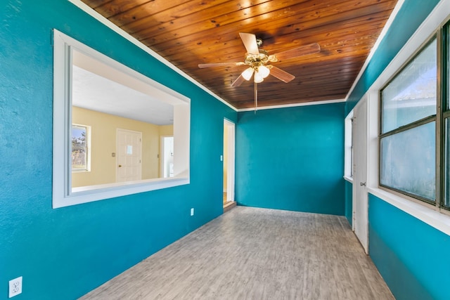 empty room with ceiling fan, a healthy amount of sunlight, wooden ceiling, crown molding, and hardwood / wood-style flooring