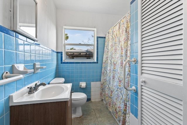 bathroom with tile patterned flooring, vanity, toilet, and tile walls