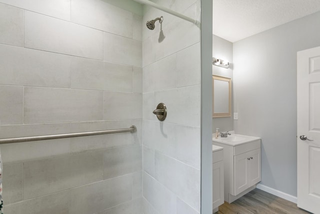 bathroom featuring wood-type flooring, vanity, a textured ceiling, and a tile shower