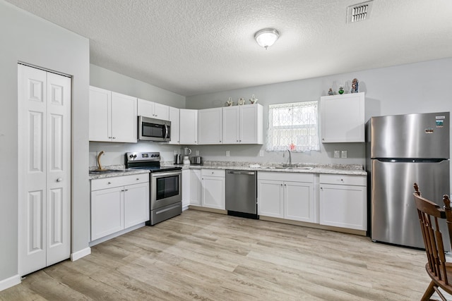 kitchen featuring sink, light hardwood / wood-style flooring, white cabinets, and appliances with stainless steel finishes