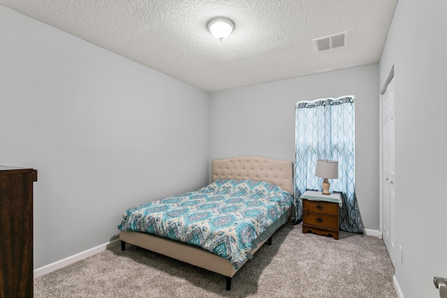 bedroom with a textured ceiling, light carpet, and a closet