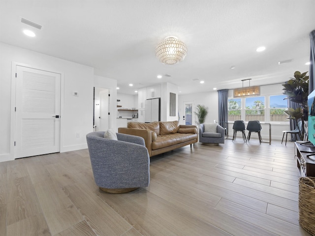 living area featuring baseboards, light wood finished floors, visible vents, and recessed lighting