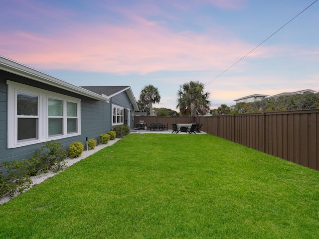 yard at dusk featuring a patio area and a fenced backyard