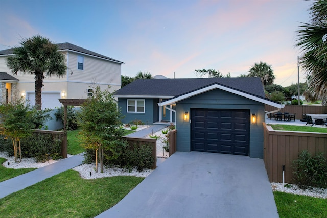 view of front of home featuring a garage, concrete driveway, a lawn, and fence