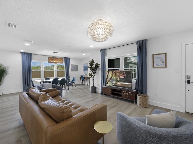 living room featuring a textured ceiling, wood finished floors, visible vents, and baseboards