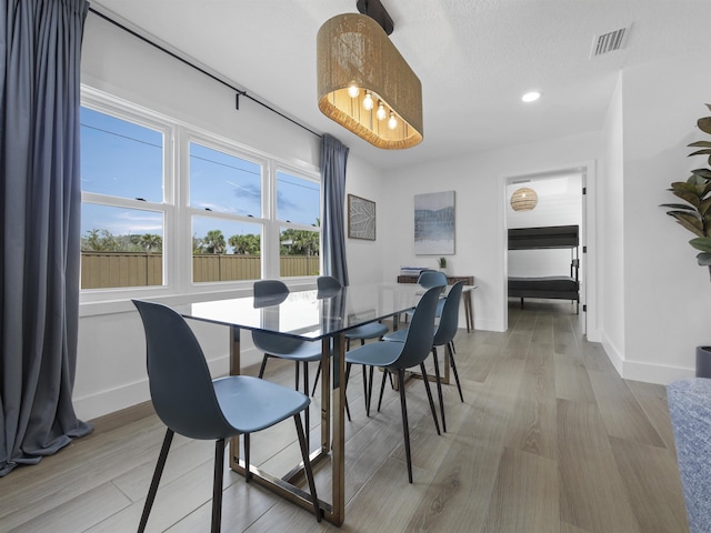 dining space with light wood-type flooring, visible vents, and baseboards