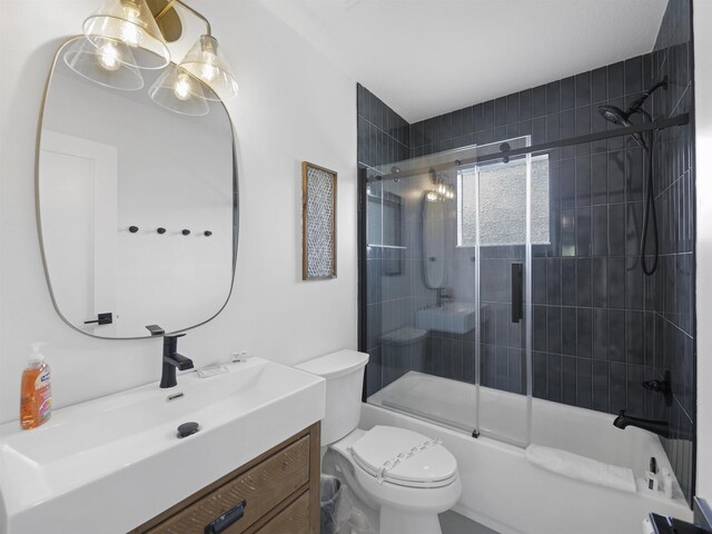 bathroom with toilet, shower / bath combination with glass door, and vanity