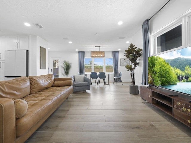 living room with light wood-style floors, recessed lighting, visible vents, and a textured ceiling