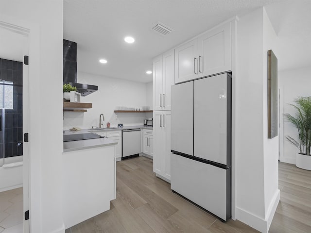 kitchen with dishwashing machine, wall chimney exhaust hood, freestanding refrigerator, open shelves, and a sink