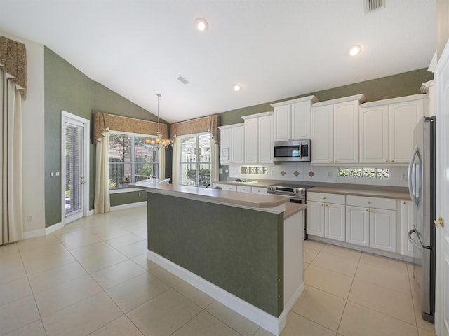 kitchen with an inviting chandelier, white cabinets, hanging light fixtures, vaulted ceiling, and stainless steel appliances