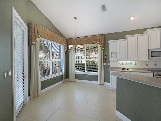 kitchen featuring white cabinetry, a notable chandelier, pendant lighting, lofted ceiling, and light tile patterned floors