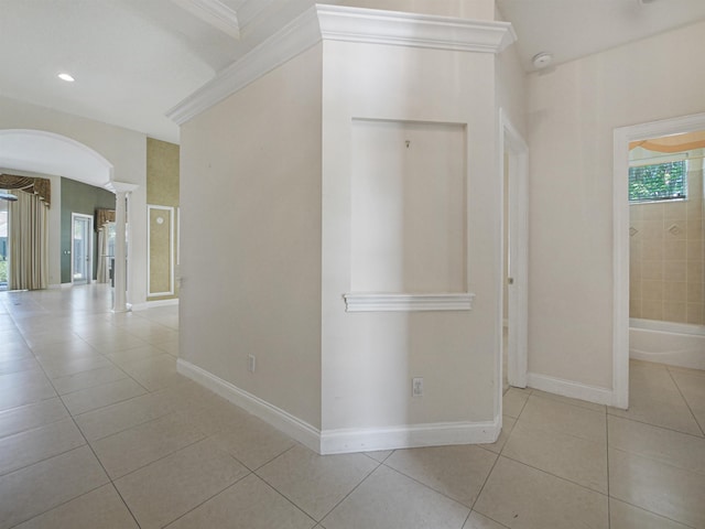 hallway featuring light tile patterned flooring, ornamental molding, and ornate columns