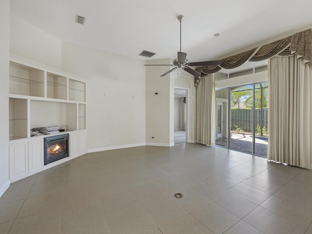 unfurnished living room featuring tile patterned flooring, built in shelves, and ceiling fan