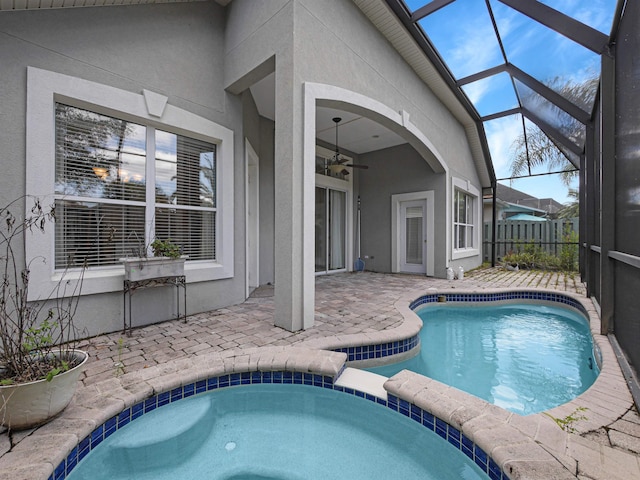 view of swimming pool with ceiling fan, glass enclosure, an in ground hot tub, and a patio