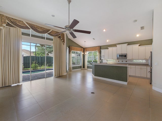 kitchen with stainless steel appliances, vaulted ceiling, ceiling fan, white cabinets, and a center island