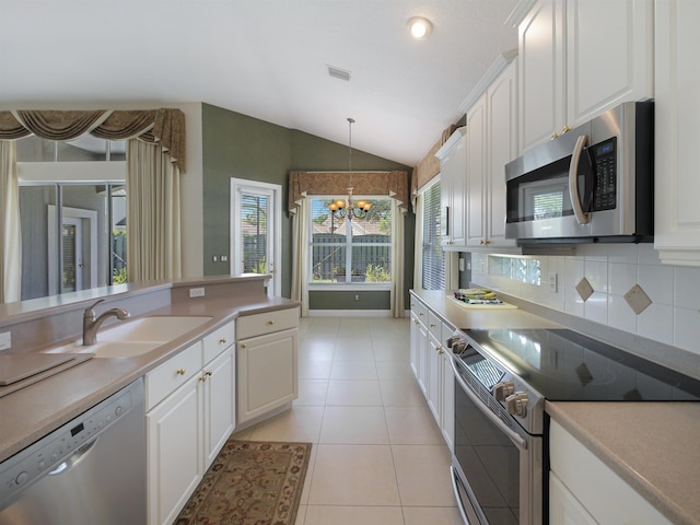 kitchen with white cabinetry, sink, stainless steel appliances, a chandelier, and vaulted ceiling