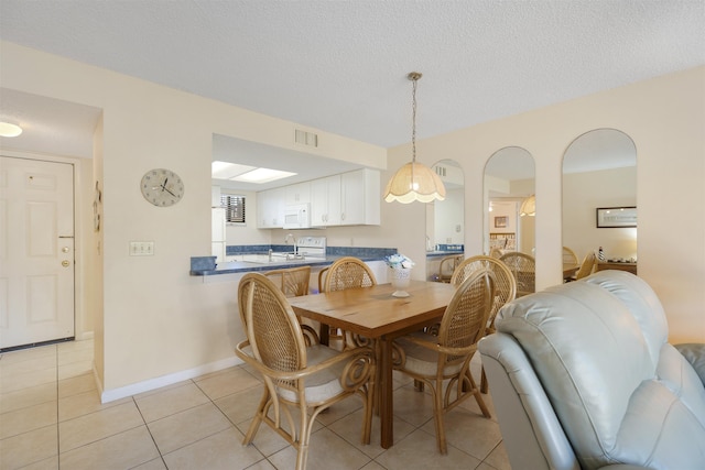 dining space with sink, light tile patterned floors, and a textured ceiling