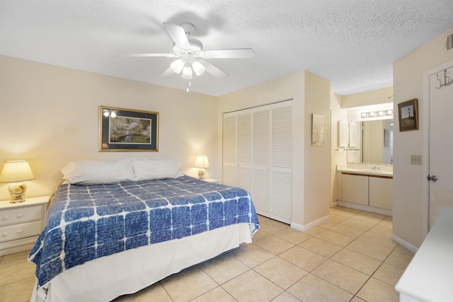 tiled bedroom with a textured ceiling, ensuite bathroom, a closet, and ceiling fan