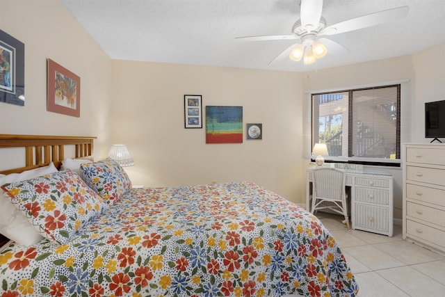 bedroom featuring ceiling fan, light tile patterned floors, and a textured ceiling