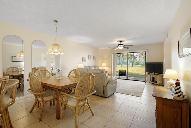 tiled dining area with ceiling fan and a textured ceiling