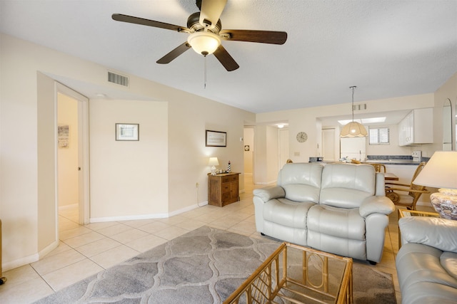 tiled living room with ceiling fan and a textured ceiling