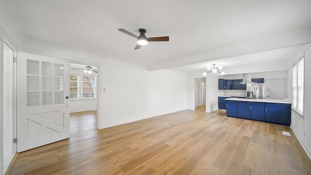 819 Mcduff Ave, Jacksonville, FL 32205 - unfurnished living room featuring baseboards, light wood finished floors, and ceiling fan with notable chandelier