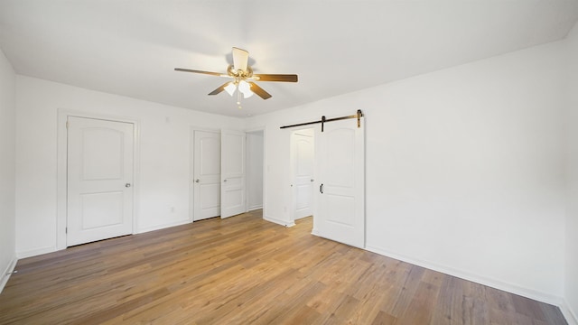 819 Mcduff Ave, Jacksonville, FL 32205 - unfurnished bedroom featuring light wood finished floors, baseboards, a ceiling fan, and a barn door