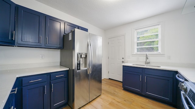 819 Mcduff Ave, Jacksonville, FL 32205 - kitchen with light wood-type flooring, stainless steel fridge, light countertops, blue cabinetry, and a sink