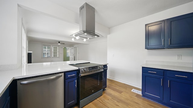 819 Mcduff Ave, Jacksonville, FL 32205 - kitchen with island exhaust hood, a peninsula, light wood-style flooring, appliances with stainless steel finishes, and blue cabinets