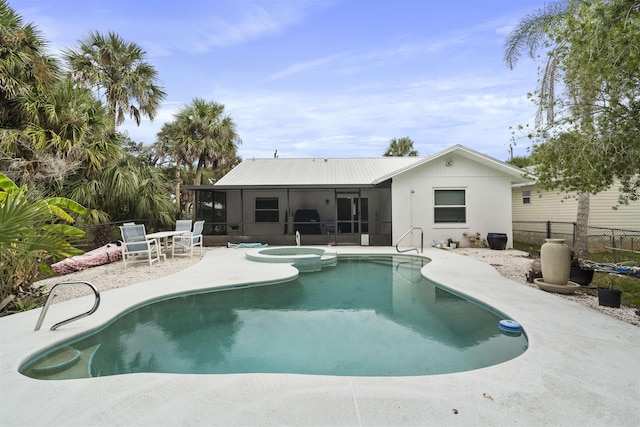 back of house featuring a sunroom, metal roof, fence, a patio area, and a pool with connected hot tub