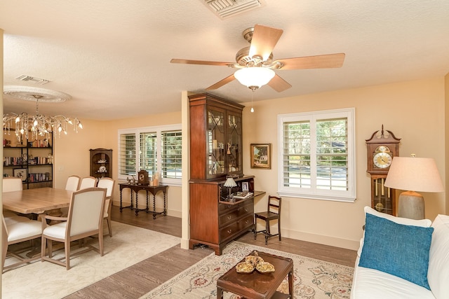 interior space with a textured ceiling, visible vents, wood finished floors, and ceiling fan with notable chandelier