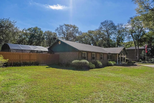 view of side of home with brick siding, fence, and a lawn