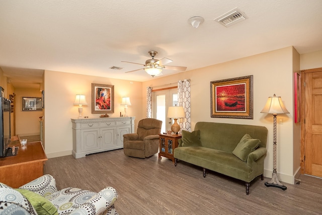 living area featuring a ceiling fan, wood finished floors, visible vents, and baseboards