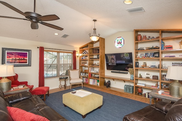 living area featuring a textured ceiling, visible vents, vaulted ceiling, and wood finished floors