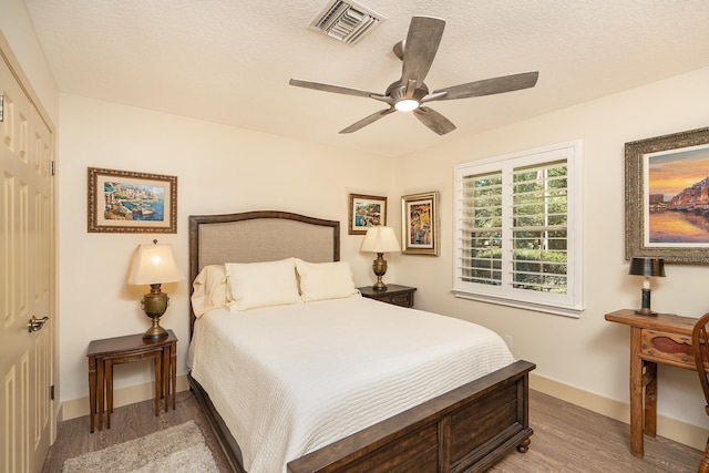 bedroom with visible vents, ceiling fan, a textured ceiling, light wood-type flooring, and baseboards