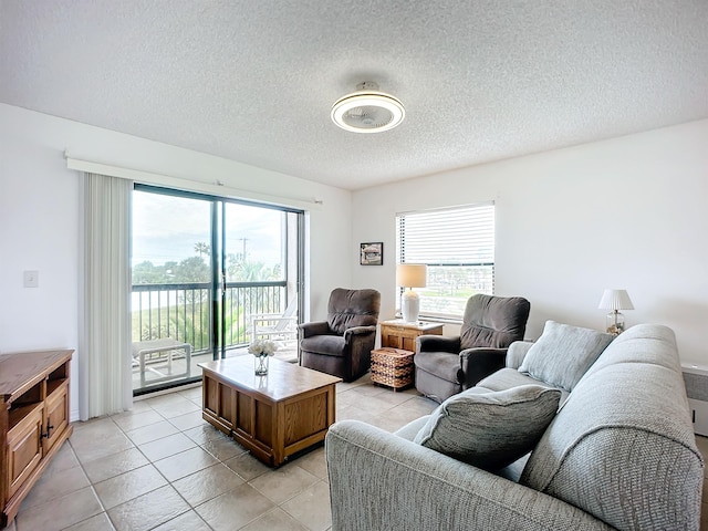 living room with light tile patterned flooring, a textured ceiling, and a water view