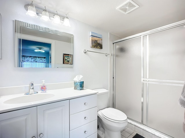 bathroom featuring vanity, toilet, tile patterned floors, visible vents, and a stall shower