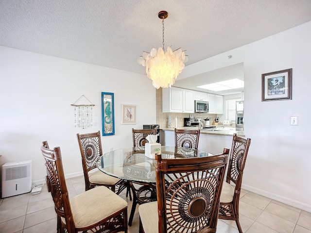 dining space with an inviting chandelier, a textured ceiling, baseboards, and light tile patterned floors