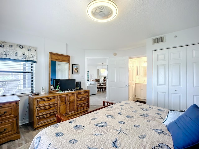 bedroom featuring a textured ceiling, a closet, light wood-style flooring, and visible vents