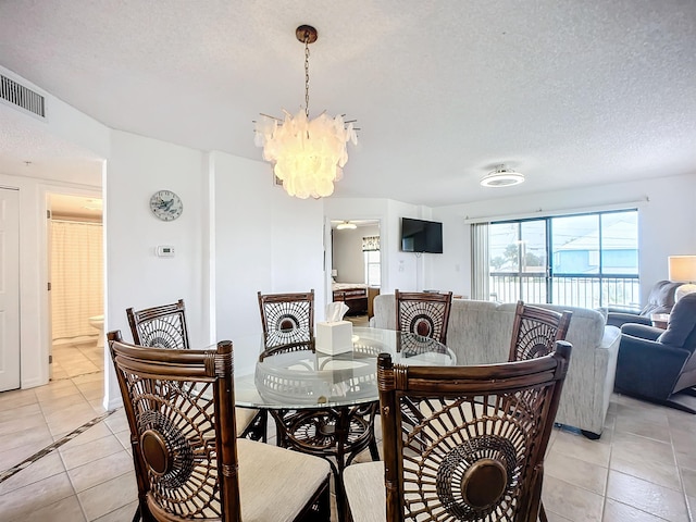 dining area featuring visible vents, a textured ceiling, light tile patterned flooring, and an inviting chandelier