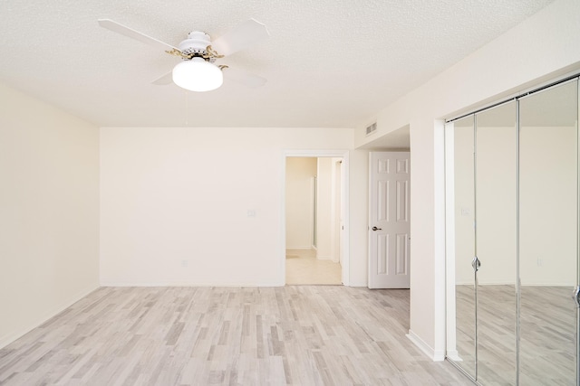 spare room with ceiling fan, a textured ceiling, and light wood-type flooring