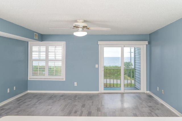 unfurnished room with plenty of natural light, a textured ceiling, ceiling fan, and light hardwood / wood-style flooring