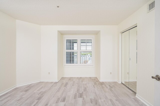 unfurnished room with a textured ceiling and light hardwood / wood-style flooring