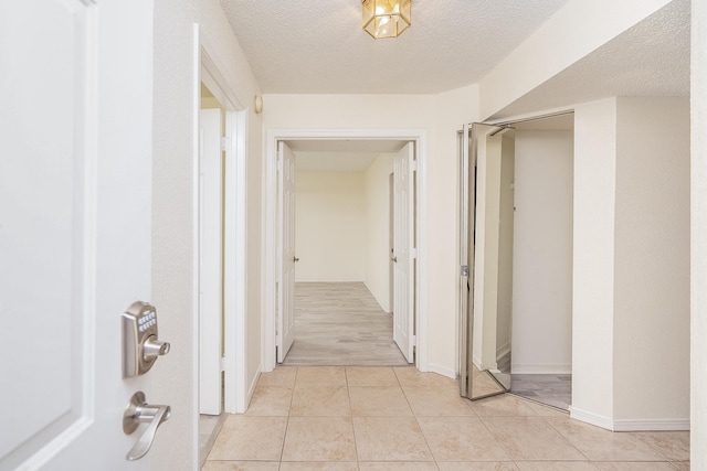 hallway featuring a textured ceiling and light tile patterned floors