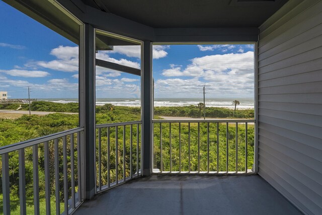 balcony with a water view and a view of the beach