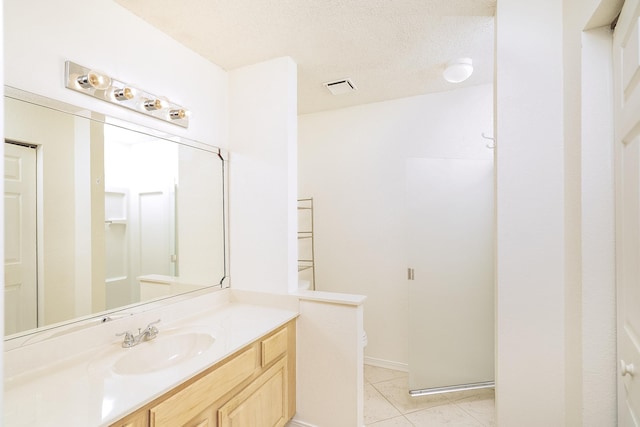 bathroom with tile patterned flooring, vanity, a textured ceiling, a shower with shower door, and toilet