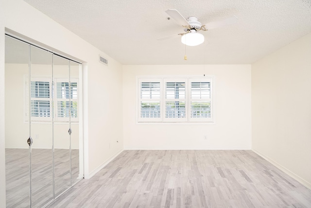 empty room featuring light hardwood / wood-style floors, a textured ceiling, and a wealth of natural light