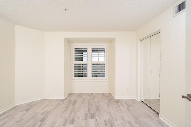 empty room featuring a textured ceiling and light hardwood / wood-style floors