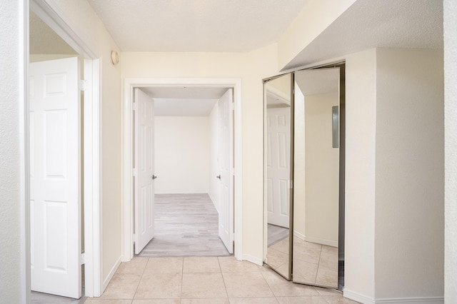 corridor with light tile patterned floors and a textured ceiling